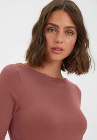 Koszulka z krótkim rękawem, okrągłym dekoltem w kolorze przybrudzonego różu. Gładka tekstura, dopasowany krój, minimalna ilość szwów, bez widocznych wzorów czy akcentów.