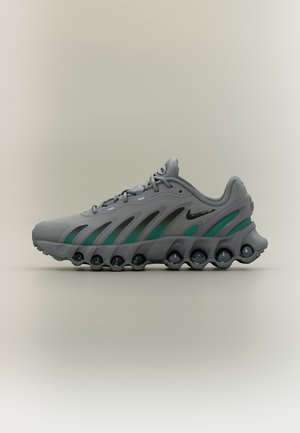 Chaussure de sport grise et verte avec semelle ondulée unique et logo Nike noir, vue de profil sur fond neutre.