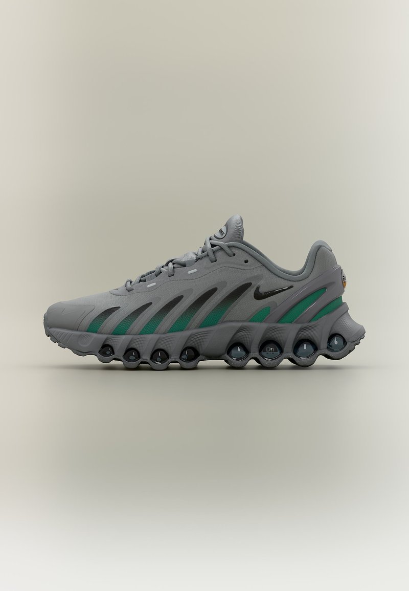 Chaussure de sport grise et verte avec semelle ondulée unique et logo Nike noir, vue de profil sur fond neutre.