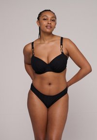 Svart bikiniset med texturerat, räfflat tyg, underwire-stöd och dekorativa remmar med guldfärgade detaljer.