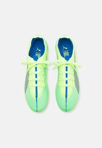 Scarpe sportive verde lime con tomaia in rete testurizzata, dettagli blu e lacci piatti. Presentano una striscia laterale grigia e un colletto imbottito.