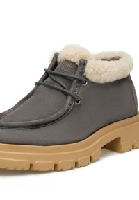 Stivaletto in camoscio grigio con colletto in pelliccia sintetica crema, sole in gomma e lacci grigi. Presenta una punta arrotondata e cuciture rinforzate.