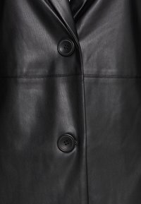 Czarna skórzana kurtka o gładkiej teksturze, z dwoma dużymi guzikami i klapami w kształcie notcha, z widocznymi detalami przeszycia.