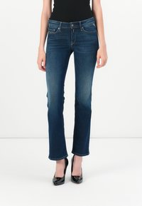 Mørkeblå, utsvingte jeans med middels høy midje, fem lommer og knappelukking. Jevn denimtekstur, ren søm.