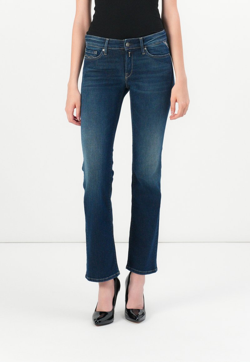Mørkeblå, utsvingte jeans med middels høy midje, fem lommer og knappelukking. Jevn denimtekstur, ren søm.