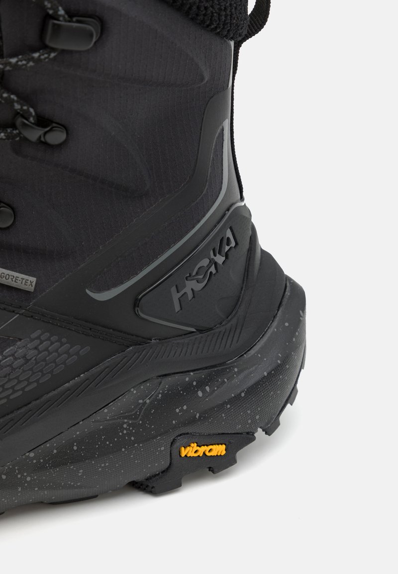 Black hiking boot featuring a textured upper, Gore-Tex material, and a Vibram outsole with a speckled design. Logo displayed on the side.