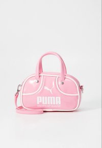 Růžová lakovaná kabelka se dvěma zaoblenými uchy, bílými akcenty a výrazným bílým logem Puma. Součástí je odnímatelný ramenní popruh.