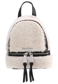 Liten krämfärgad sherpa-ryggsäck med svarta läderdetaljer, två silverfärgade dragkedjor och ett handtag på toppen.