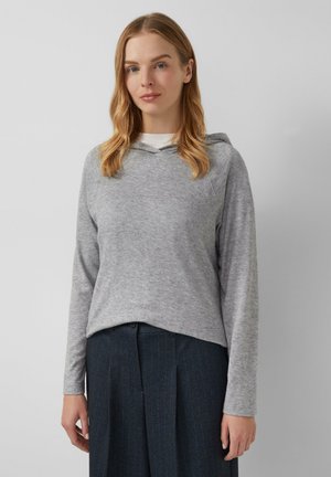Sweat-shirt à capuche gris en tissu doux, doté de manches longues et d'une coupe décontractée, associé à un pantalon foncé à rayures.
