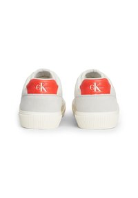Białe sneakersy z szarymi zamszowymi akcentami i czerwonym logo na pięcie. Posiadają teksturowaną gumową podeszwę oraz wyściełany kołnierz dla wygody.