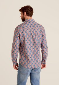 T-shirt met tropische print met een roze achtergrond en blauwe palmbomenpatronen. Lange mouwen, button-down kraag en een relaxte pasvorm.