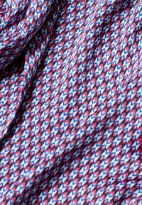 Bomullstyg med ett upprepat geometriskt mönster av små röda, blå och vita diamanter, med en slät textur och mjuk fall.