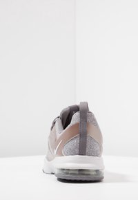 Scarpe da ginnastica in tessuto grigio con suola bianca ammortizzata, parte superiore in mesh, dettagli rinforzati e linguetta sul retro.