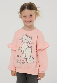 Różowy sweter z falbanami na rękawach i grafiką kota w koronie. Napisy brzmią "Jestem tak Purrfekcyjny" z złotymi akcentami.