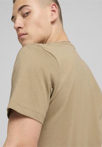 Light brown cotton t-shirt with a crew neck and short sleeves, featuring a fitted silhouette and smooth texture.