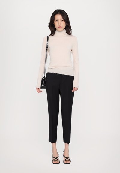 Light beige turtleneck sweater, black tailored pants with frayed bottom, black crossbody bag, strappy black heeled sandals.