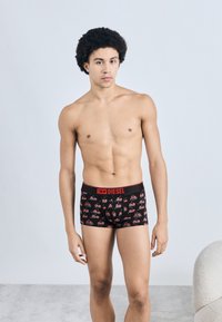 Fekete boxernadrág piros derékpánttal, rajta ismétlődő minta rajzfilmes piros cipőkkel és szemüvegekkel. Sima, rugalmas anyagból készült.