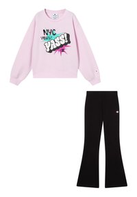 Sudadera rosa con texto gráfico "NYC VIBES? YASS!" y pantalones de campana negros con pequeño logo de Champion en el lateral. Ambos hechos de una tela suave.