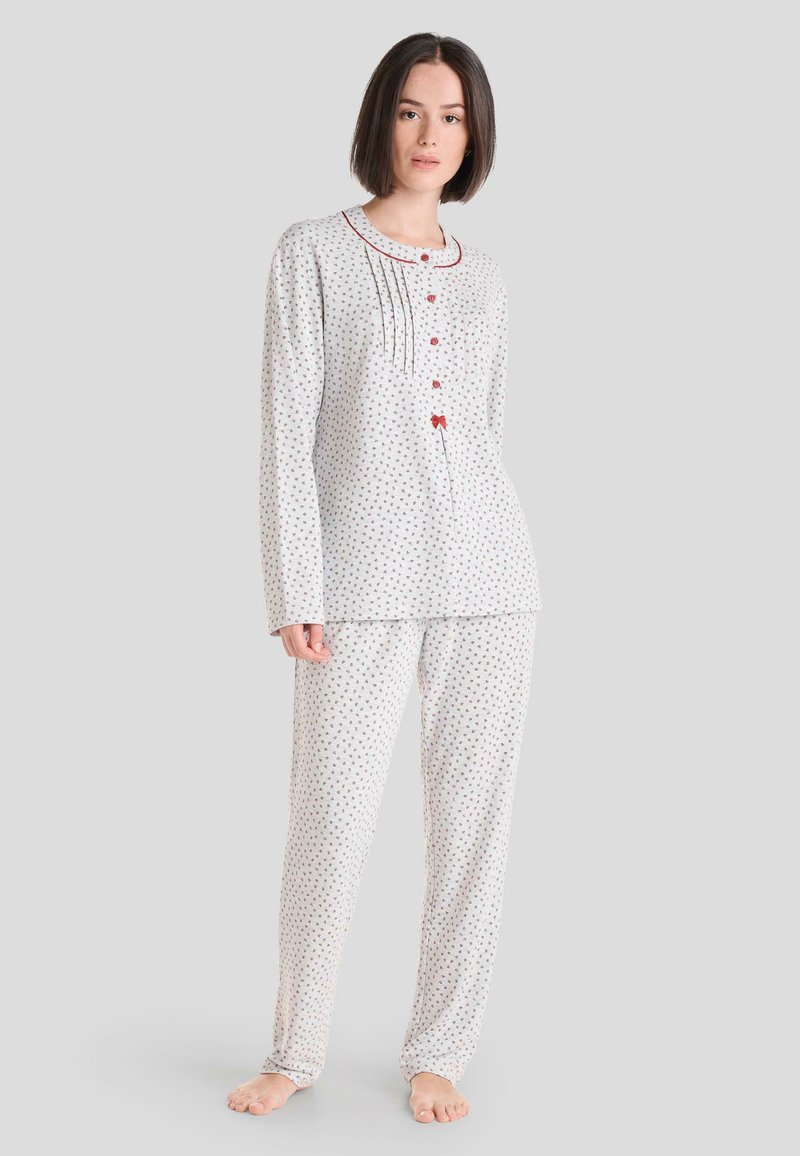 Conjunto de pijama de algodón ligero en blanco con pequeño estampado floral rojo, que incluye una camisa abotonada con pliegues y pantalones sueltos a juego.