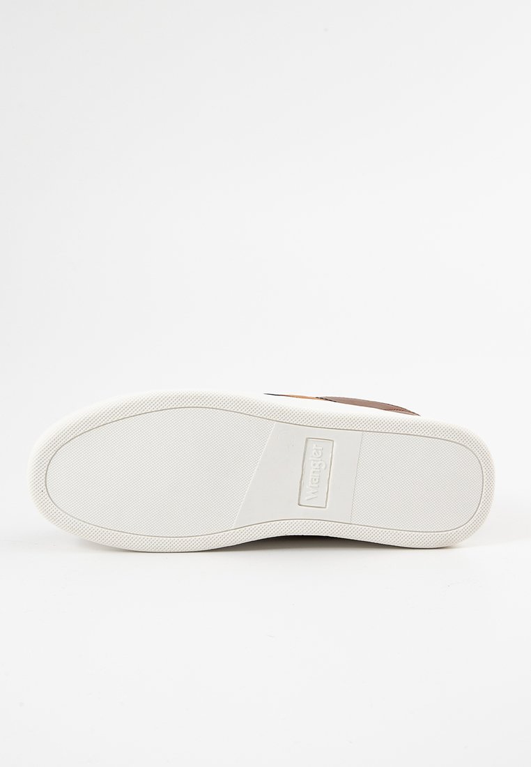 Zapato de cuero marrón con una suela de goma blanca, que cuenta con una plantilla texturizada y un detalle de logo característico en la suela. Diseño clásico de corte bajo.