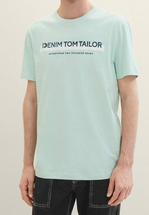 Camiseta de manga corta de un suave color verde menta claro, con cuello redondo, que presenta texto de marca en azul marino y blanco en el frente. Material de algodón suave.