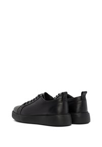 Black leather sneakers with a smooth finish, round toe, and tonal laces. Features a cushioned sole and rear pull tab for ease of wear.