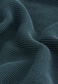 Tissu texturé en bleu sarcelle foncé avec des nervures en forme de vagues, affichant une apparence douce et un éclat subtil. Idéal pour les vêtements ou l'ameublement.