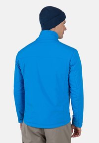 Sininen eristetty takki korkealla kauluksella ja sileällä pinnalla, jossa on pitkät hihat ja suora leikkaus. Yhdistetty tummansinisen pipon kanssa.