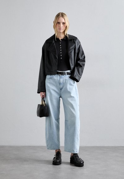 Giacca cropped in ecopelle nera, top nero con bottoni, jeans a gamba larga blu chiaro, scarpe nere stringate, piccola borsa nera con dettagli dorati.