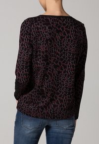 Blusa de manga larga con un patrón de print animal oscuro en tonos de negro, burdeos y gris, con un escote redondo y acentos de manga en negro.