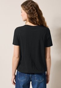 Sort kortærmet t-shirt med rund halsudskæring, der har en afslappet pasform og glat tekstur, parret med blå denim jeans.