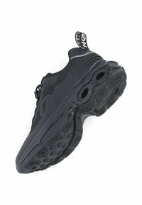 Zwarte sport sneaker met dikke, gestructureerde zool, cirkelpatronen op de buitenzool, een trekloop met witte tekst en een bovenwerk van mesh materiaal.
