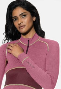 Haut ajusté à manches longues rose avec col haut et fermeture éclair. Comprend un panneau contrastant bordeaux et des accents de coutures dorées.