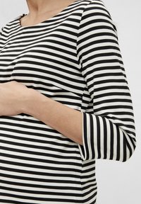 Mustavalkoinen raidallinen paita, jossa on veneen muotoinen kaula-aukko ja kolme neljäsosaista hihaa. Valmistettu pehmeästä kankaasta, jossa on rento istuvuus ja vaakaraitoja.