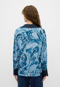 Camicia a maniche lunghe con un motivo paisley blu, tessuto leggero, colletto e polsini blu navy, e una vestibilità morbida, caratterizzata da dettagli intricati in tutto il capo.