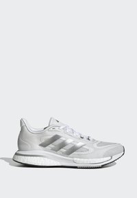 Weiße Sportschuh mit strukturiertem Mesh-Obermaterial, silbernen Akzenten, drei horizontalen Streifen und einer gepolsterten Sohle. Abgerundete Zehenpartie und Schnürverschluss.