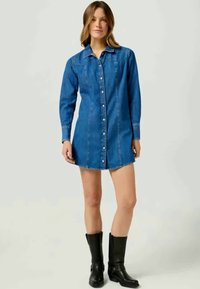 Denimist kleit, pikad varrukad, nööpidega esikülg, helesinine värv, figureeritud siluett, kontrastne õmblus, kantud mustade saapatega.