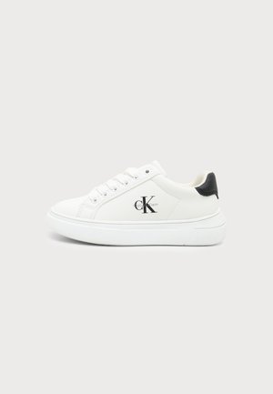 Hvid lavtopsneakers med sort hældetalje og Calvin Klein-logo på siden, set fra ydersiden mod en ensfarvet baggrund.