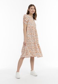 Blumenkleid in Hellorange mit kurzen Puffärmeln, gerafftem Mieder und gestuftem Rock. Das Muster zeigt kleine blaue und orangefarbene Blumen.