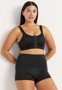 Zwarte draadloze bh met brede banden, sluiting aan de voorkant met haakjes en bijpassende high-waisted short gemaakt van soepele, rekbare stof.