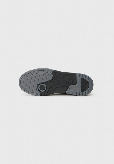 Black and gray sneaker sole featuring textured rubber, circular accent, and intricate tread pattern for grip and durability.