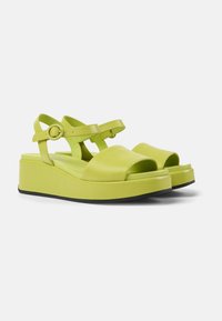 Sandali platform verde lime con cinturino largo e fibbia regolabile. Presentano pelle liscia, punta aperta e suola sagomata per il comfort.