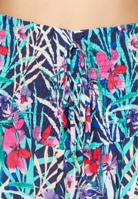 Tela con estampado floral en colores vibrantes de azul, rosa y verde, con una superficie texturizada y un cordón ajustable en la cintura.