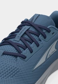 Μπλε αθλητικό παπούτσι με δίχτυ, με σκούρα μπλε κορδόνια, ετικέτα «Escalante 4» στη γλώσσα και λογότυπο «Altra» στο πλάι κοντά στη σόλα.