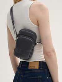 Sac bandoulière noir en simili cuir texturé avec deux compartiments zippés, une bandoulière ajustable et un logo de marque gravé.