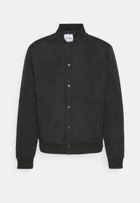 Veste bomber noire en tissu lisse, dotée d'un col montant, de boutons-pression, de poignets côtelés et d'un ourlet avec un aspect légèrement brillant.