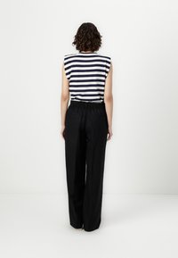 Striped sleeveless top in navy and white, paired with high-waisted, loose black pants with an elastic waistband and two back pockets.