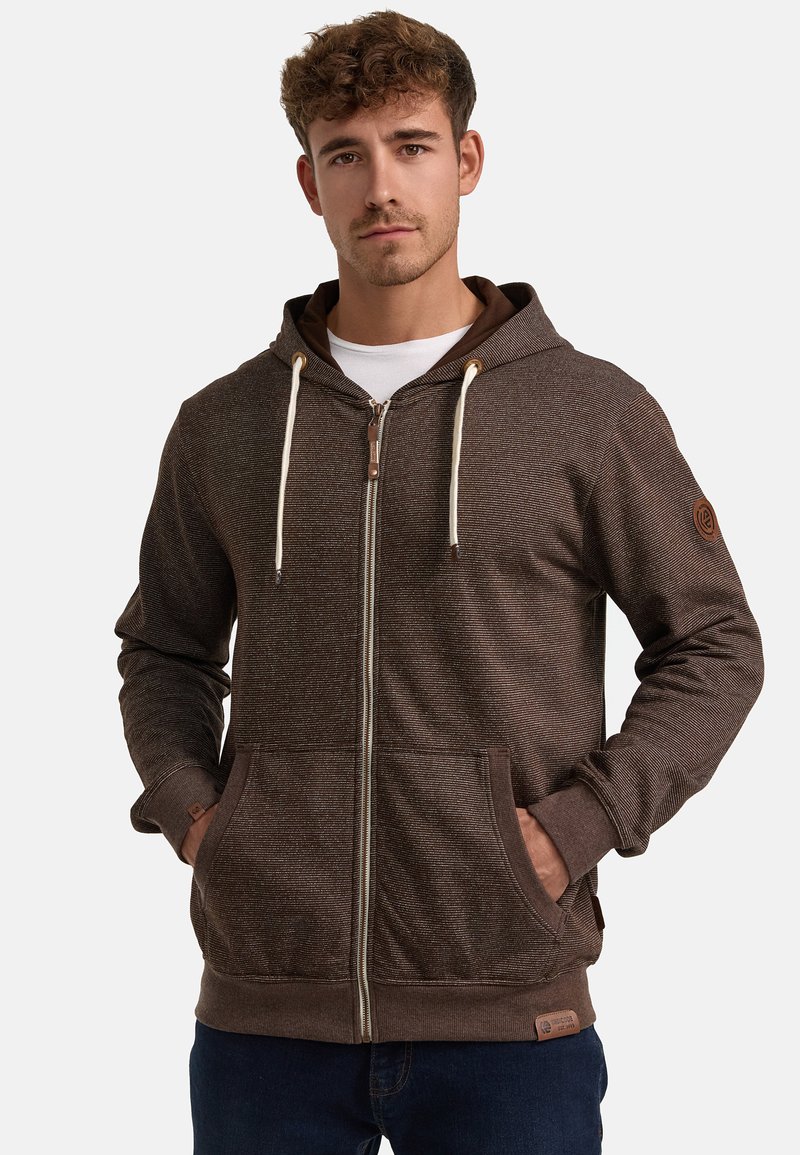 Brown zip-up hoodie with a textured surface, adjustable drawstrings, front pockets, and a logo patch on the sleeve.