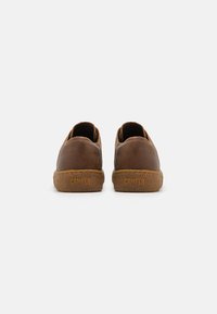 Brūnas ādas slip-on kurpes ar brūnu gumijas zoli. Iezīmētas ar teksturētu apdari un nospiestu "CAMPER" logotipu aizmugurē.