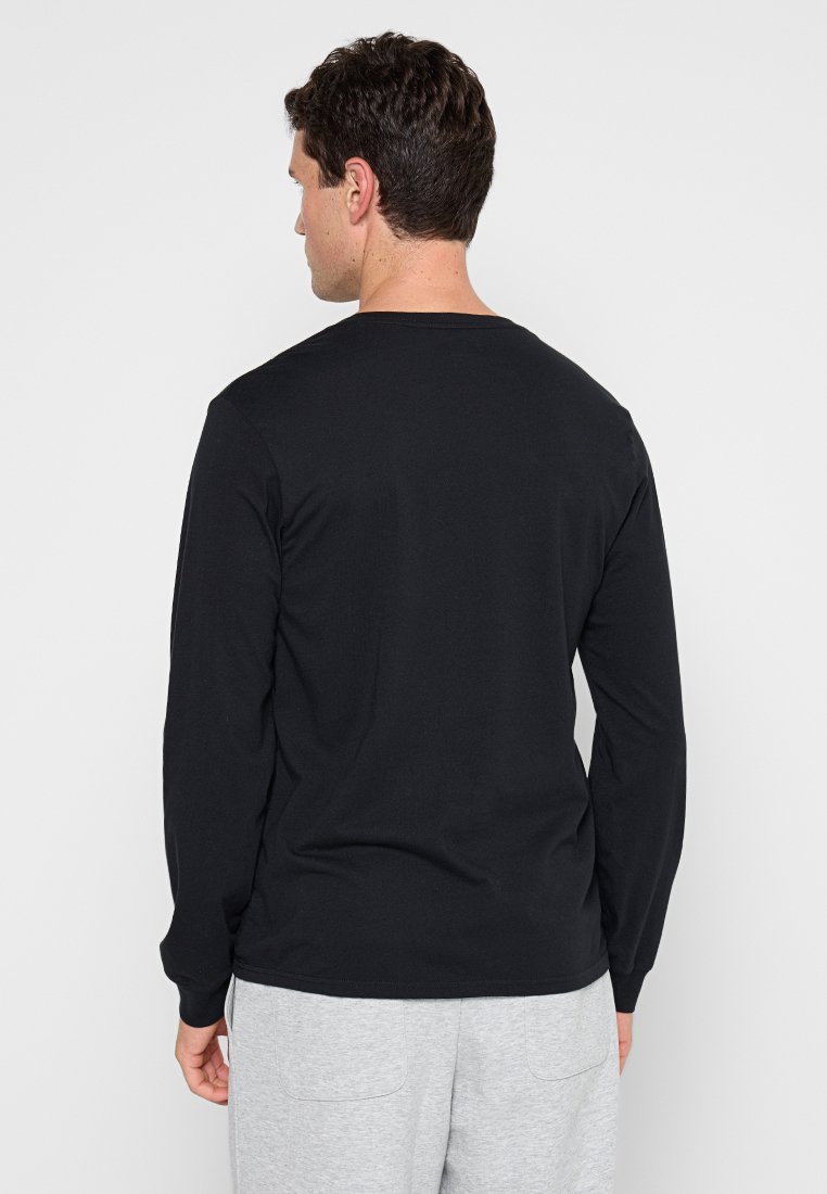 Camiseta de manga larga negra, hecha de algodón. Presenta un cuello redondo y un dobladillo recto, con una textura suave y un diseño minimalista.